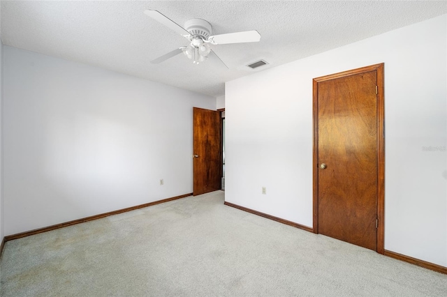 unfurnished bedroom with ceiling fan, light colored carpet, and a textured ceiling