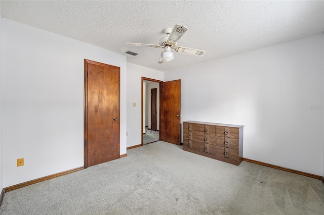 unfurnished bedroom featuring light carpet, a textured ceiling, and ceiling fan