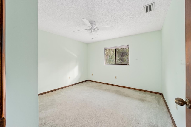 empty room with ceiling fan, light carpet, and a textured ceiling