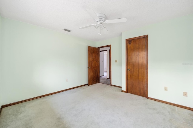 unfurnished bedroom featuring ceiling fan, light carpet, and a textured ceiling