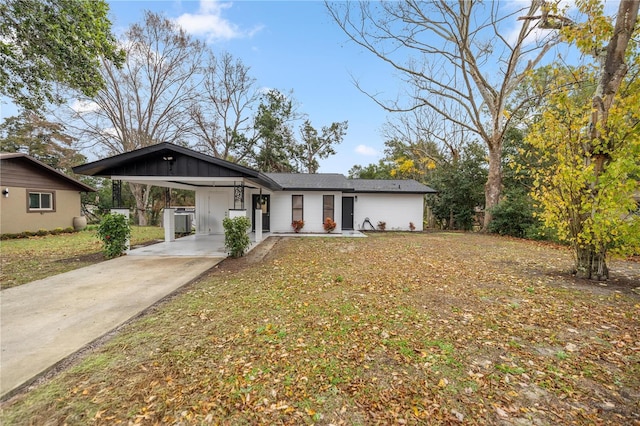 view of front of property featuring a carport, board and batten siding, a front yard, and driveway