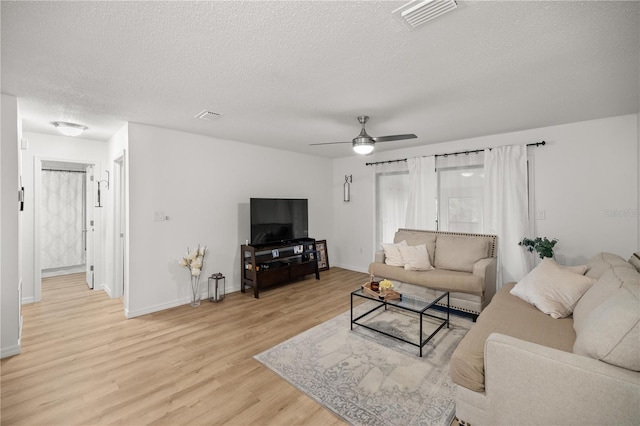 living area with a ceiling fan, visible vents, light wood-style flooring, and a textured ceiling