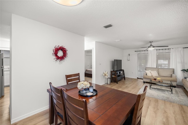 dining space with visible vents, a textured ceiling, and light wood-style flooring