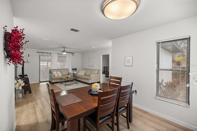 dining room featuring visible vents, a ceiling fan, a textured ceiling, light wood-type flooring, and baseboards