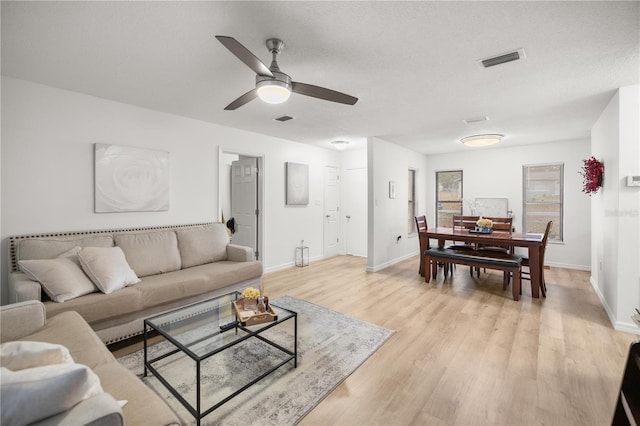 living room featuring light wood-type flooring, baseboards, and visible vents