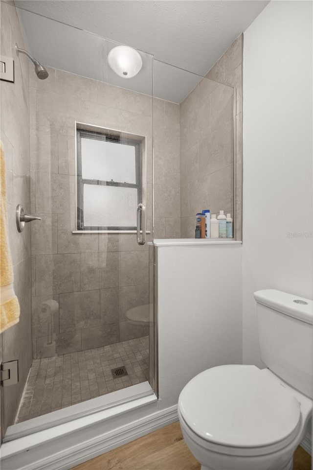 bathroom featuring wood finished floors, a shower stall, and toilet