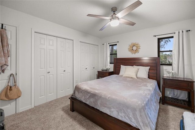 carpeted bedroom featuring ceiling fan and two closets