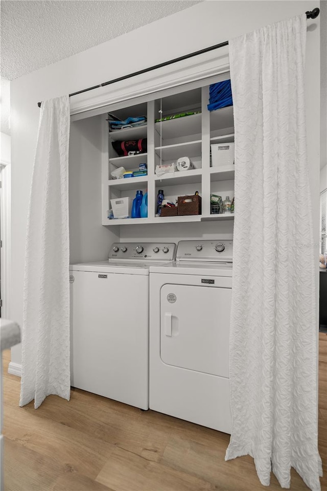 laundry room with a textured ceiling, laundry area, light wood finished floors, and independent washer and dryer