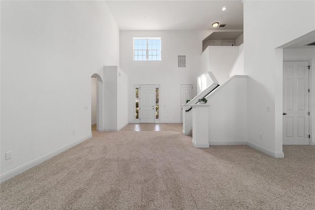 carpeted entrance foyer with a towering ceiling