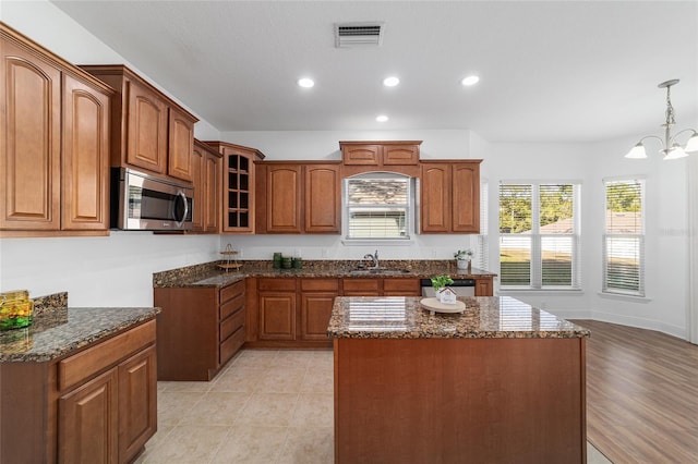 kitchen featuring appliances with stainless steel finishes, decorative light fixtures, sink, dark stone countertops, and a chandelier