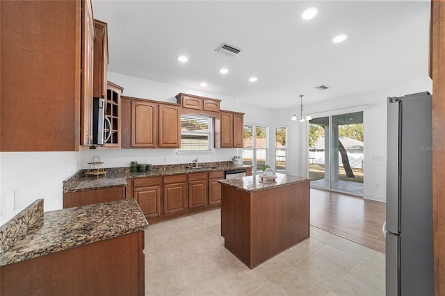 kitchen with a center island, hanging light fixtures, dark stone countertops, appliances with stainless steel finishes, and a notable chandelier