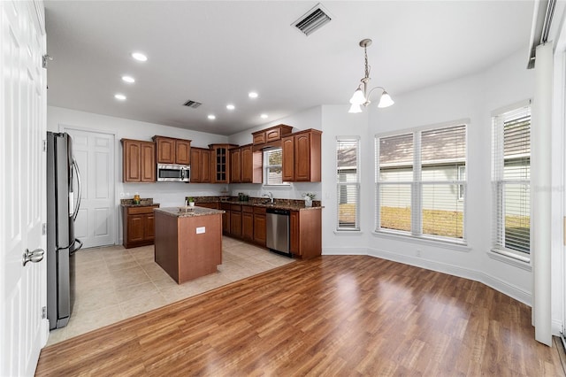 kitchen featuring an inviting chandelier, a center island, appliances with stainless steel finishes, pendant lighting, and light hardwood / wood-style floors