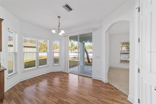 unfurnished dining area featuring dark wood-type flooring and an inviting chandelier