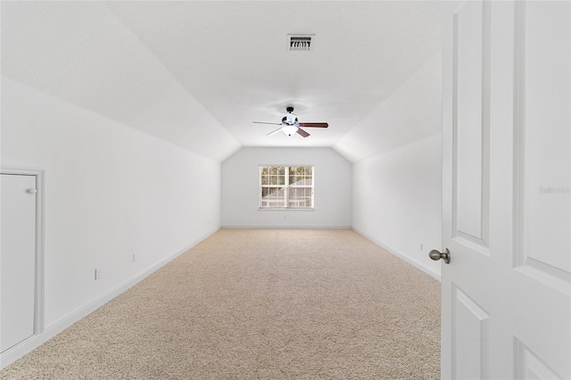 additional living space featuring a textured ceiling, vaulted ceiling, ceiling fan, and carpet