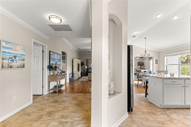 corridor featuring a notable chandelier, crown molding, and a textured ceiling