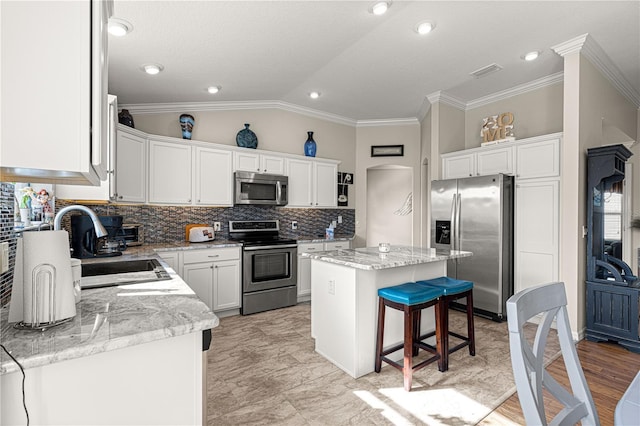 kitchen featuring light stone counters, stainless steel appliances, a center island, and white cabinets