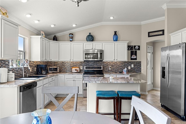 kitchen with white cabinetry, appliances with stainless steel finishes, sink, and a kitchen island