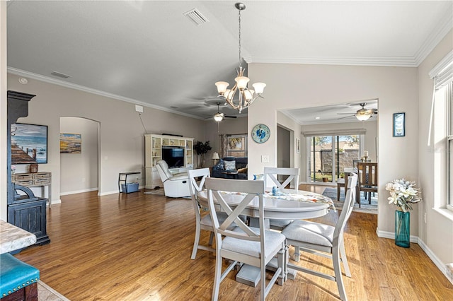 dining room with vaulted ceiling, crown molding, ceiling fan with notable chandelier, and hardwood / wood-style floors