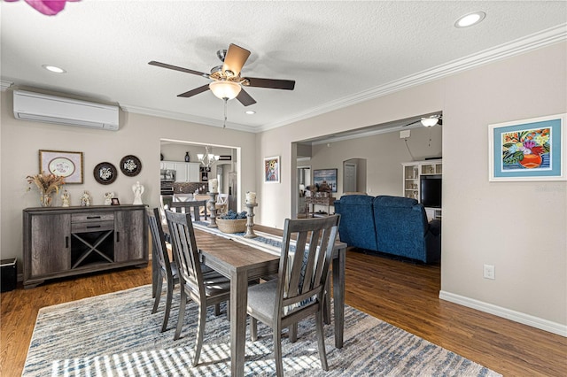 dining area featuring dark wood-type flooring, a wall mounted AC, ornamental molding, a textured ceiling, and ceiling fan with notable chandelier