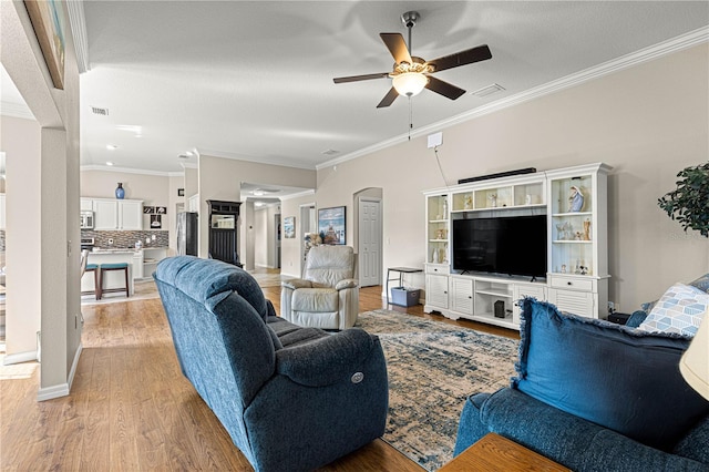 living room featuring crown molding, ceiling fan, and light wood-type flooring