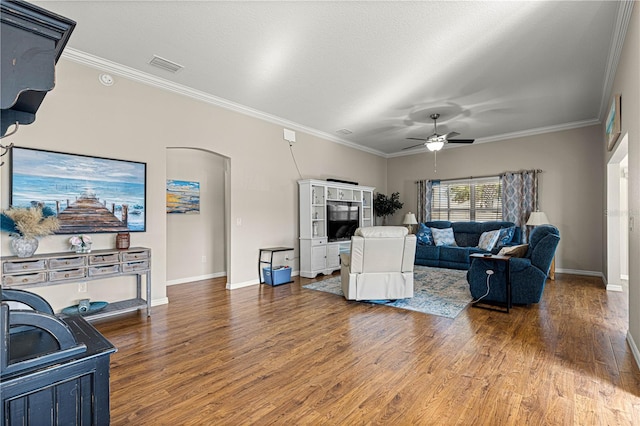 living room with a textured ceiling, wood-type flooring, ornamental molding, and ceiling fan