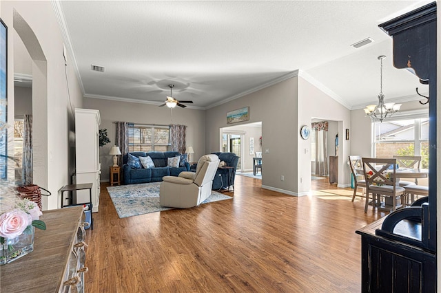 living room with crown molding, vaulted ceiling, a textured ceiling, hardwood / wood-style flooring, and ceiling fan with notable chandelier