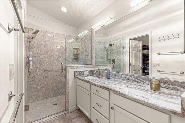 bathroom featuring an enclosed shower, vanity, and vaulted ceiling