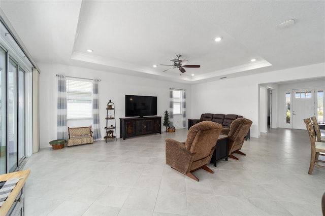 living room featuring ceiling fan and a raised ceiling