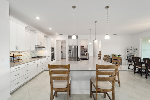 kitchen with sink, hanging light fixtures, stainless steel appliances, decorative backsplash, and white cabinets