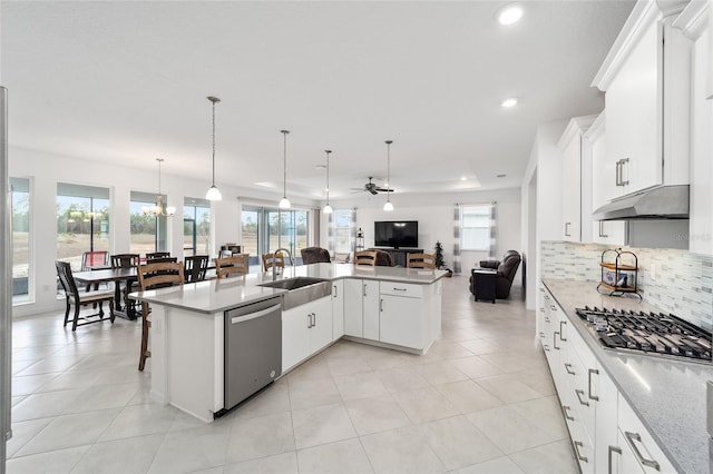 kitchen with stainless steel appliances, sink, white cabinets, and decorative light fixtures