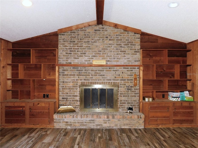 unfurnished living room featuring hardwood / wood-style flooring, a fireplace, wooden walls, and vaulted ceiling with beams