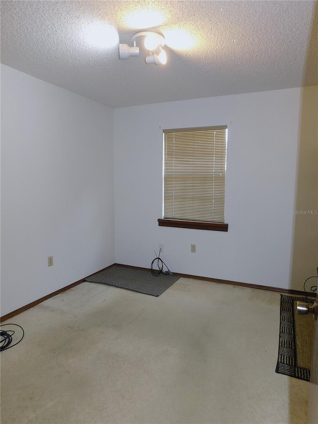 carpeted empty room featuring a textured ceiling