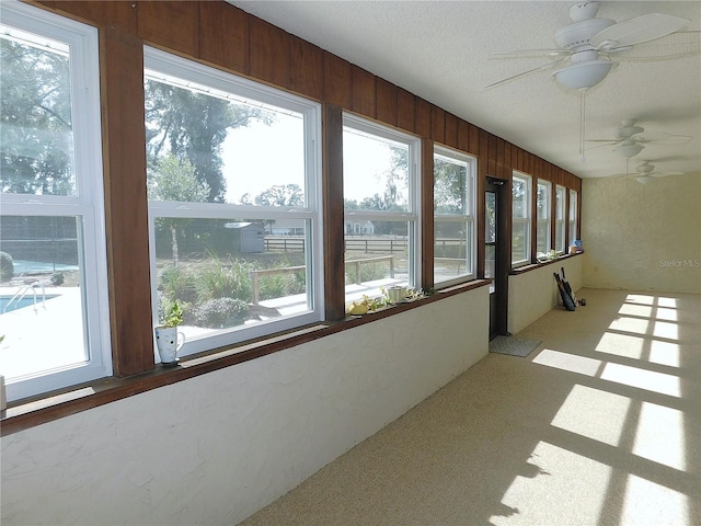 unfurnished sunroom with ceiling fan