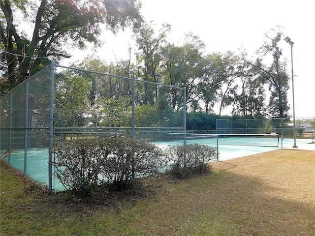 view of tennis court with a yard