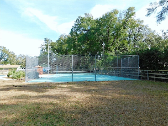 view of tennis court featuring a lawn