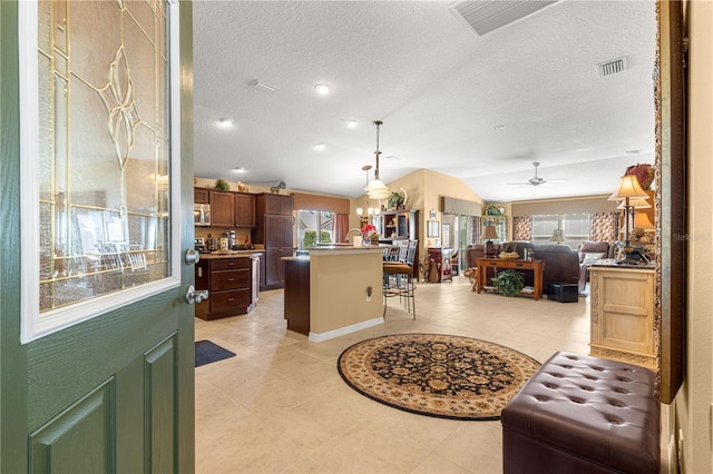 kitchen with ceiling fan, a center island, a textured ceiling, decorative light fixtures, and vaulted ceiling