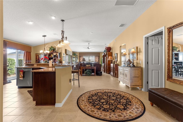 kitchen with light tile patterned flooring, a kitchen bar, dishwasher, pendant lighting, and a kitchen island with sink