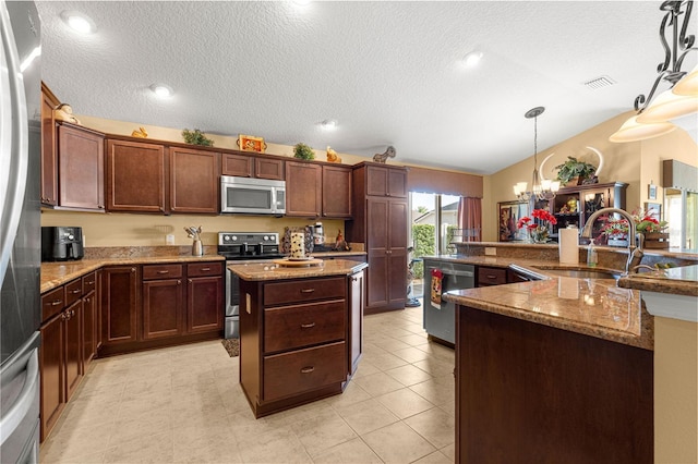 kitchen with lofted ceiling, sink, decorative light fixtures, a center island, and appliances with stainless steel finishes