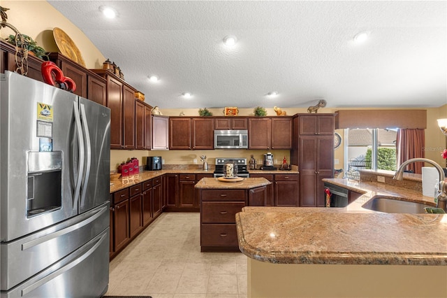 kitchen with lofted ceiling, sink, a kitchen island with sink, stainless steel appliances, and a textured ceiling