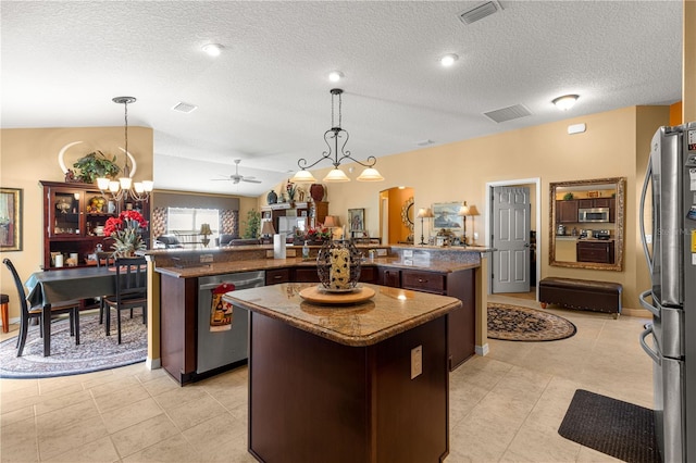 kitchen featuring appliances with stainless steel finishes, pendant lighting, a center island, dark brown cabinetry, and a textured ceiling