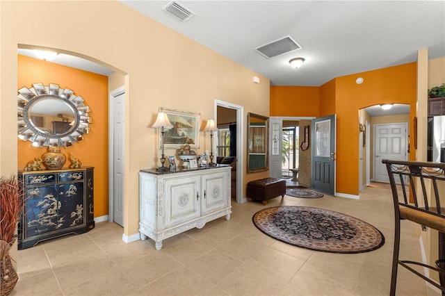 hall with light tile patterned flooring and a textured ceiling