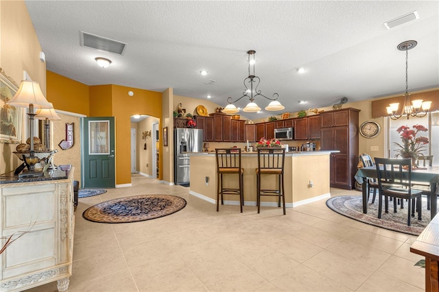 kitchen with stainless steel appliances, an island with sink, hanging light fixtures, and a breakfast bar area