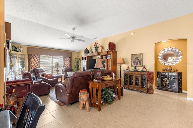 tiled living room featuring ceiling fan, lofted ceiling, and a textured ceiling