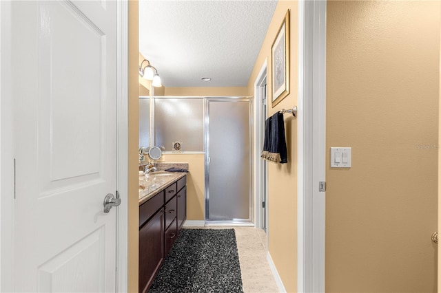 bathroom featuring vanity, an enclosed shower, and a textured ceiling