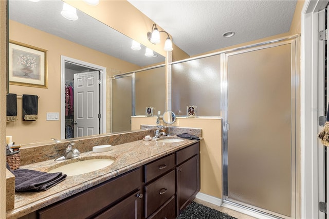 bathroom featuring vanity, a textured ceiling, and walk in shower