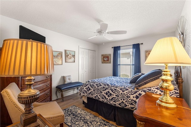 bedroom with ceiling fan, hardwood / wood-style floors, a closet, and a textured ceiling