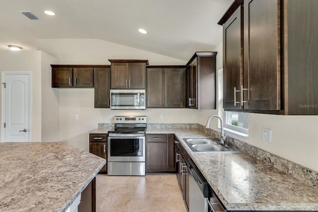 kitchen featuring dark brown cabinets, stainless steel appliances, light stone counters, lofted ceiling, and sink