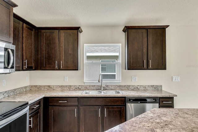 kitchen featuring dark brown cabinetry, stainless steel appliances, a textured ceiling, and sink