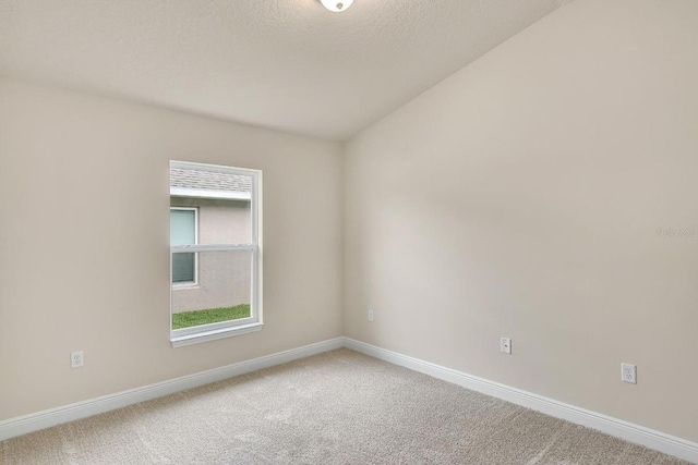 carpeted spare room featuring a textured ceiling and vaulted ceiling