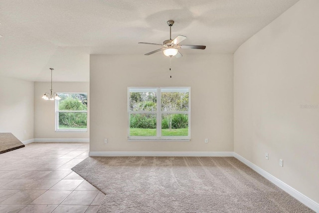 spare room featuring light tile patterned flooring, ceiling fan with notable chandelier, and a textured ceiling